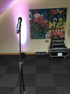 A small outdoor PA with leaded microphone on a stand and two speakers